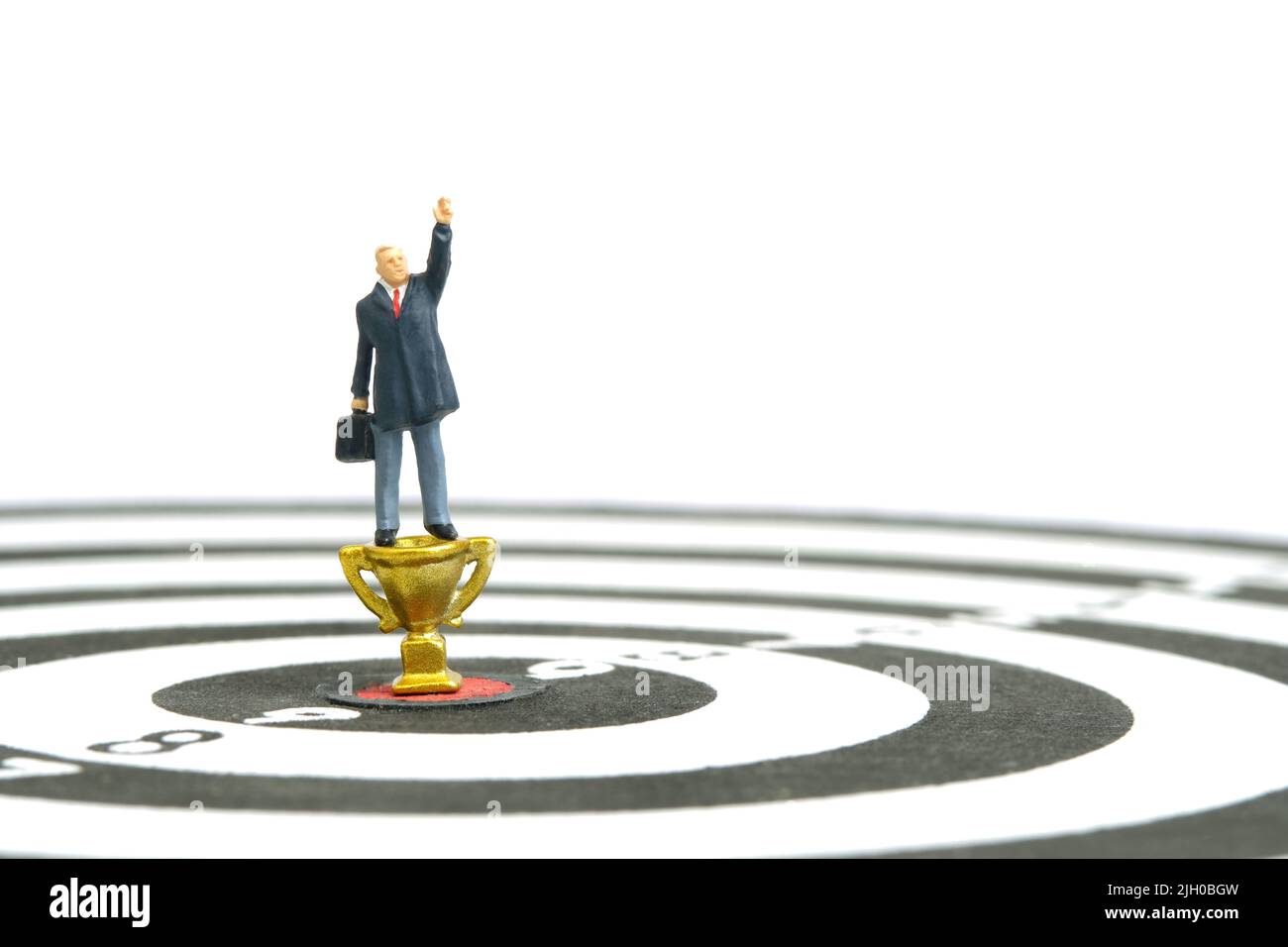 Fotografia di personaggi giocattolo in miniatura. Un uomo d'affari determinato che punta al trofeo d'oro per vincere o diventare un vincitore. Isolato su sfondo bianco. Immagine Foto Stock