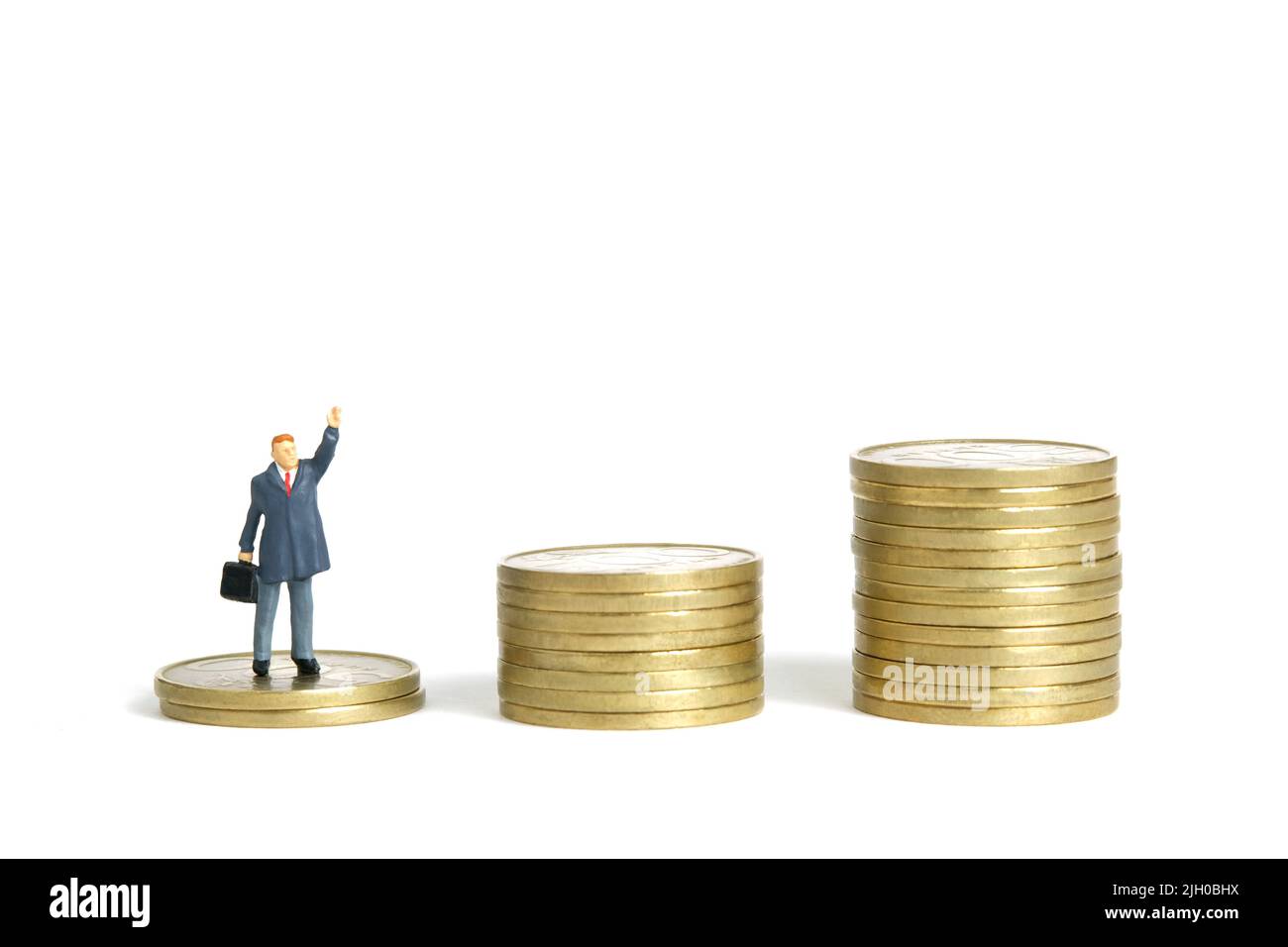 Fotografia di personaggi giocattolo in miniatura. Concetto di piano di libertà finanziaria. Un uomo d'affari in piedi sopra di moneta mucchio scala mentre alza la sua mano. IO Foto Stock
