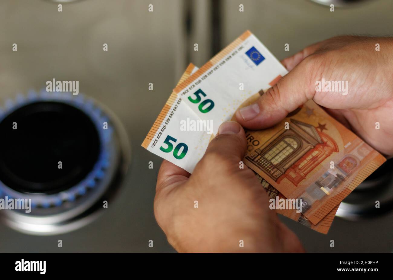 Banconote in euro in mano, denaro in mano, banconote in mano su un bruciatore a gas, aumento dei prezzi del gas Foto Stock