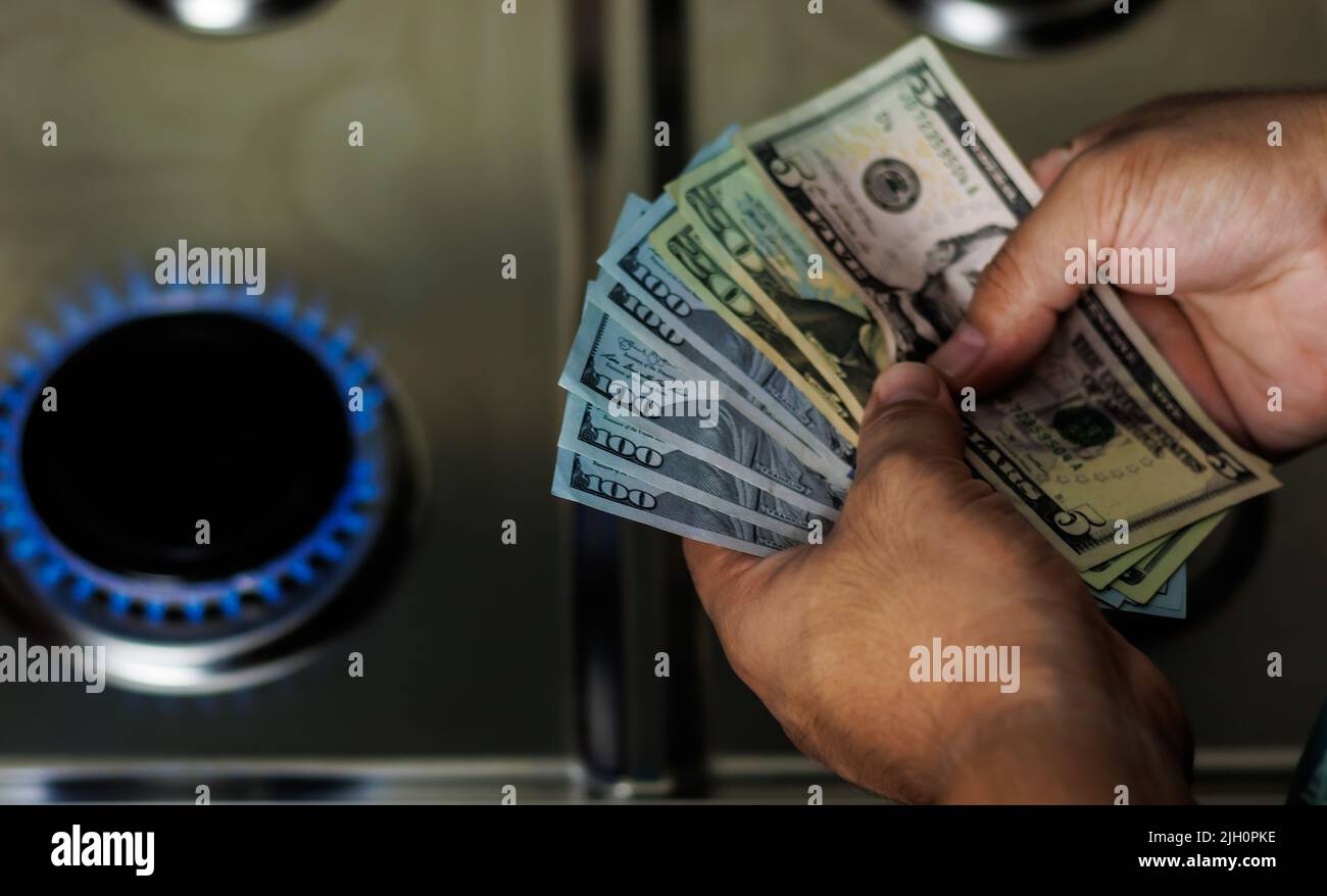Banconote in euro in mano, denaro in mano, banconote in mano su un bruciatore a gas, aumento dei prezzi del gas Foto Stock
