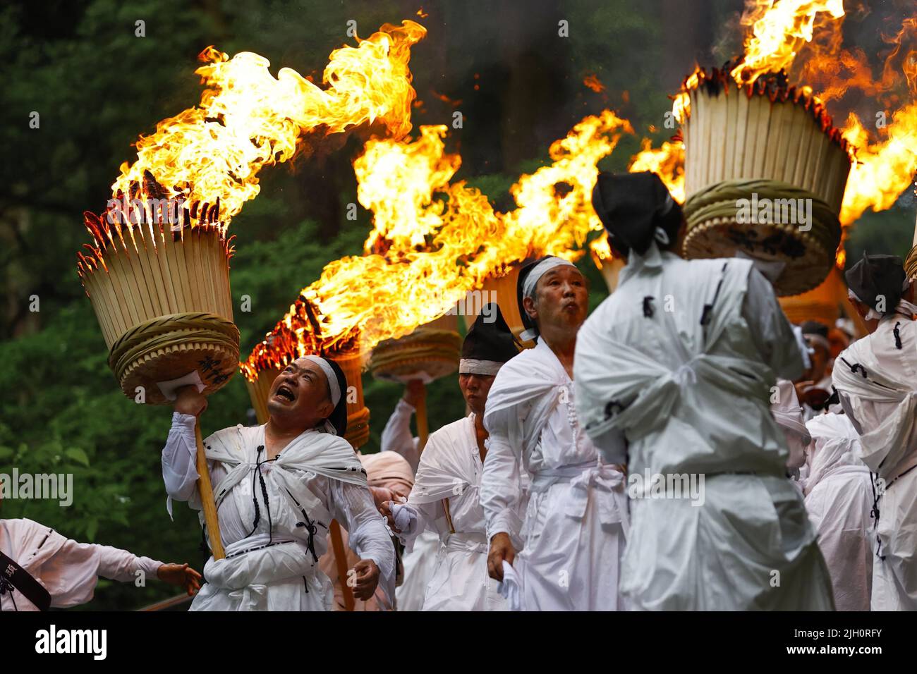 Nachikatsuura, Giappone occidentale, 14 luglio 2022. Gli uomini bianchi tengono le fiammeggianti torce durante un festival annuale del fuoco presso il santuario di Kumano Nachi Taisha, patrimonio mondiale dell'umanità, nella città della prefettura di Wakayama, Nachikatsuura, Giappone occidentale, il 14 luglio 2022. (Kyodo)==Kyodo Photo via Credit: Newscom/Alamy Live News Foto Stock