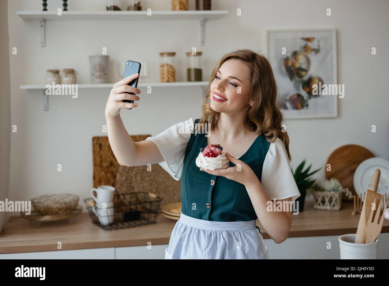 Bella ragazza prende un selfie con una torta in cucina Foto Stock