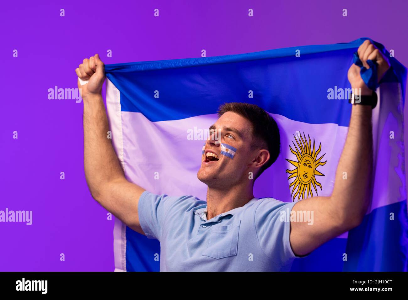 Felice caucasico uomo sostenitore con bandiera di argentina su illuminazione rosa Foto Stock