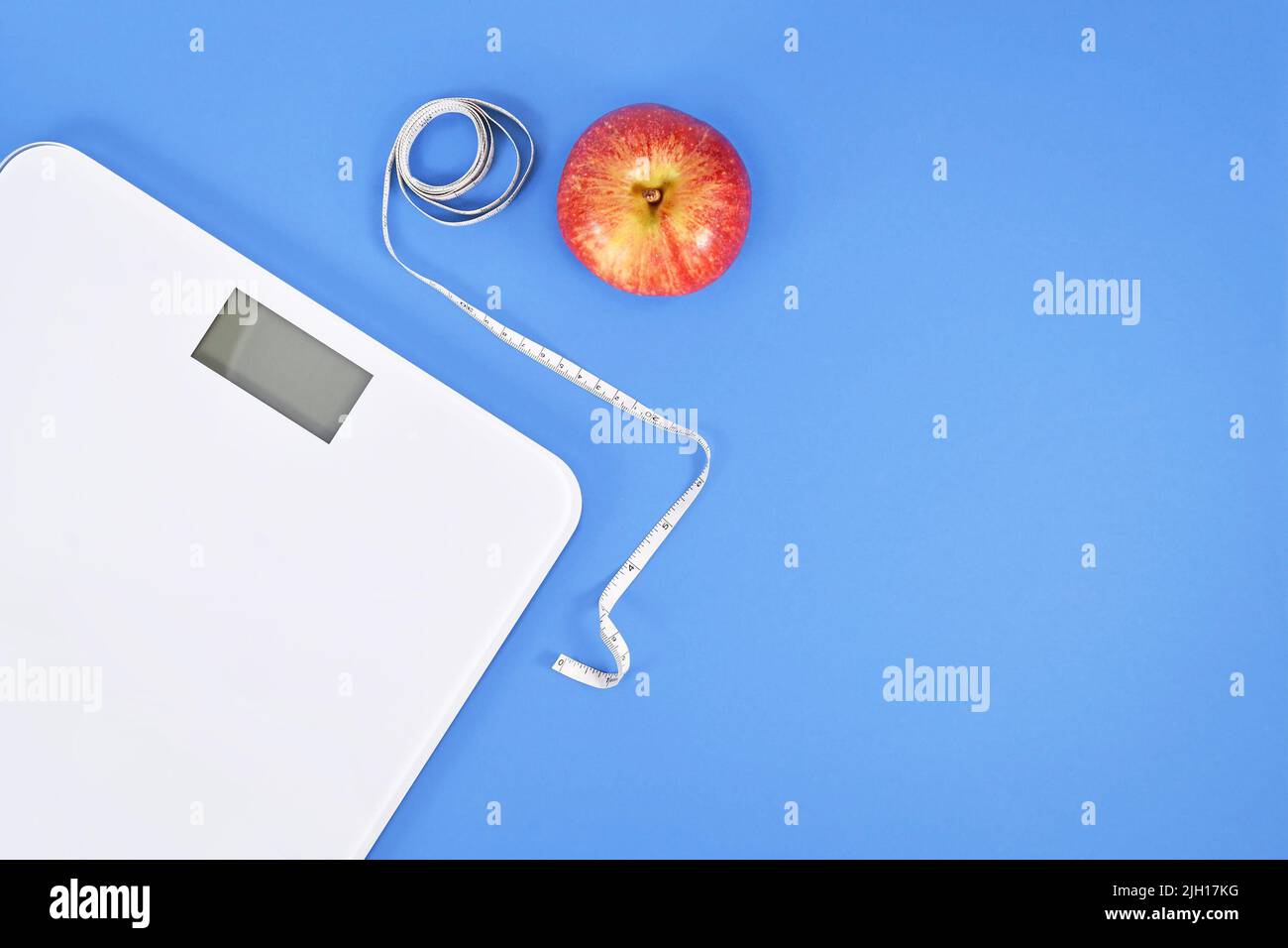Concetto di dieting con scala, nastro di misurazione e mela su sfondo blu con spazio di copia Foto Stock