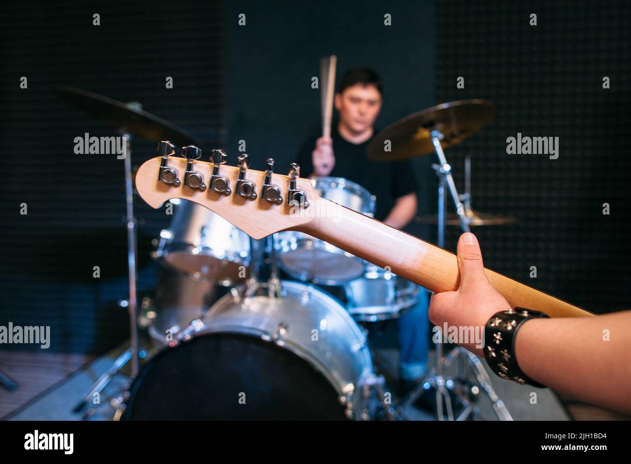 Primo piano del collo della chitarra sullo sfondo del drum set Foto Stock