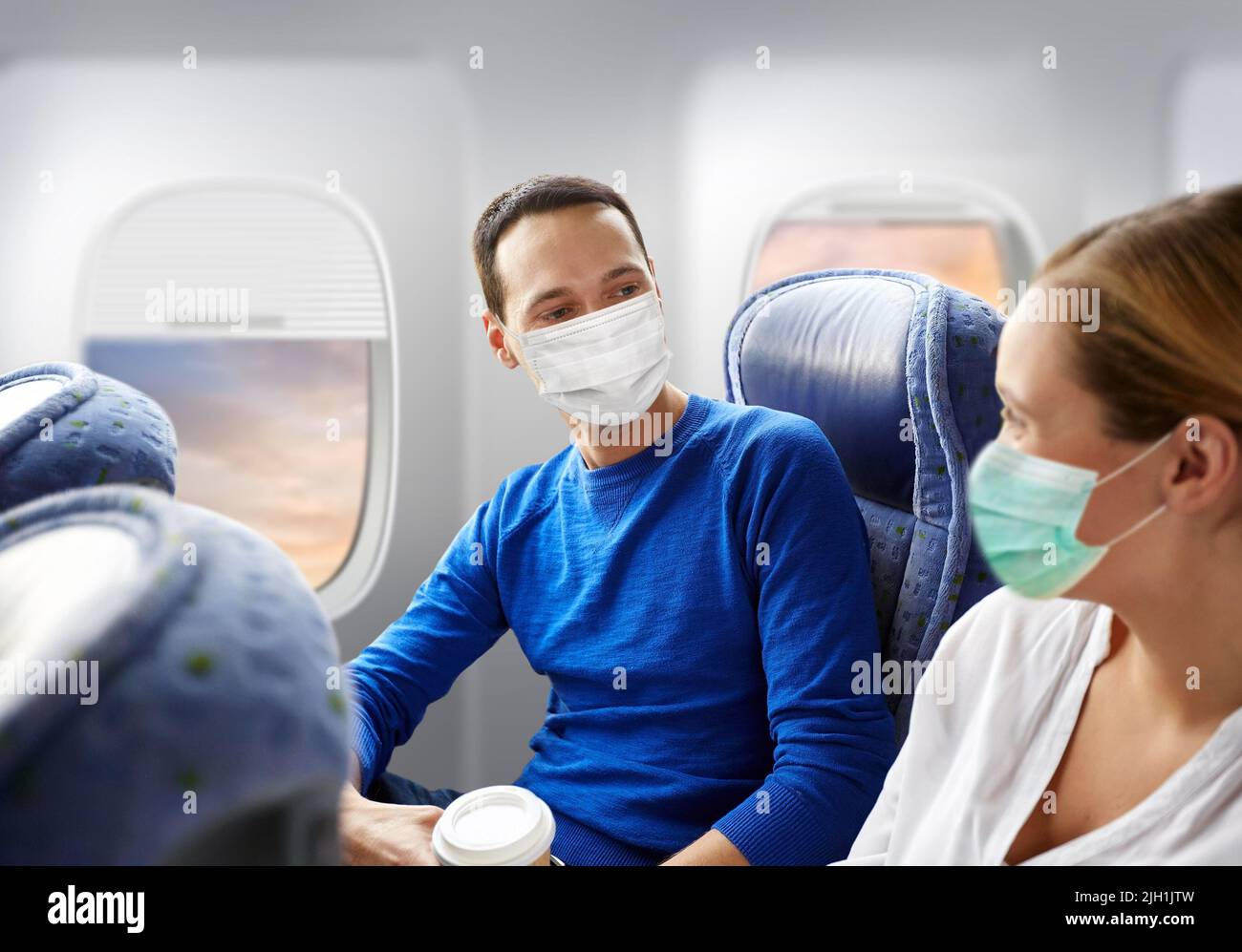 coppia di passeggeri in maschere che viaggiano in aereo Foto Stock