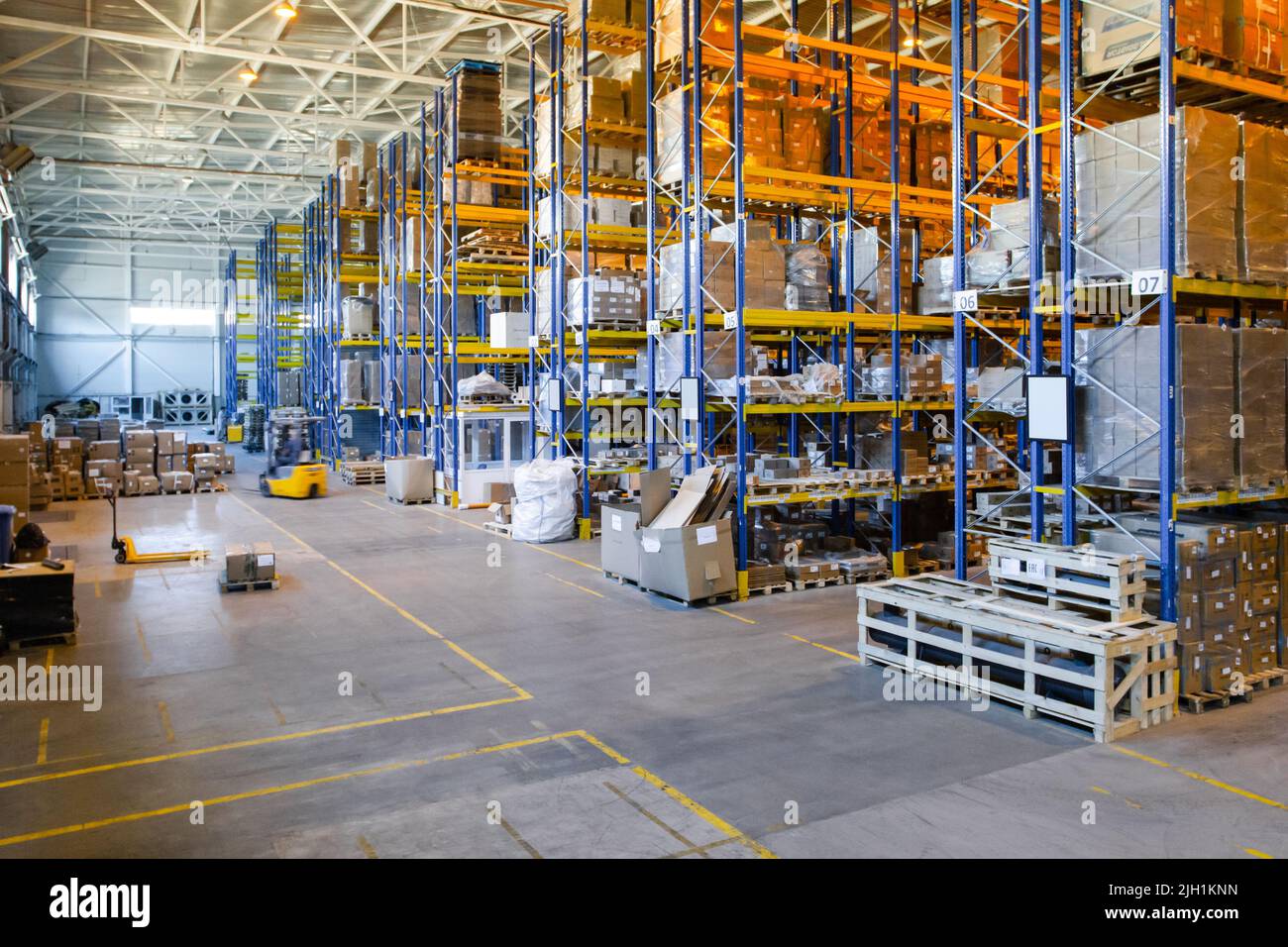 Interno di un magazzino moderno di negozi al dettaglio con transpallet vicino ai ripiani Foto Stock