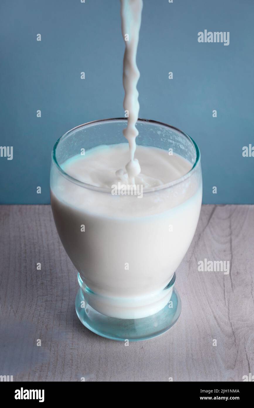 Versare il latte in un bicchiere sul tavolo Foto Stock