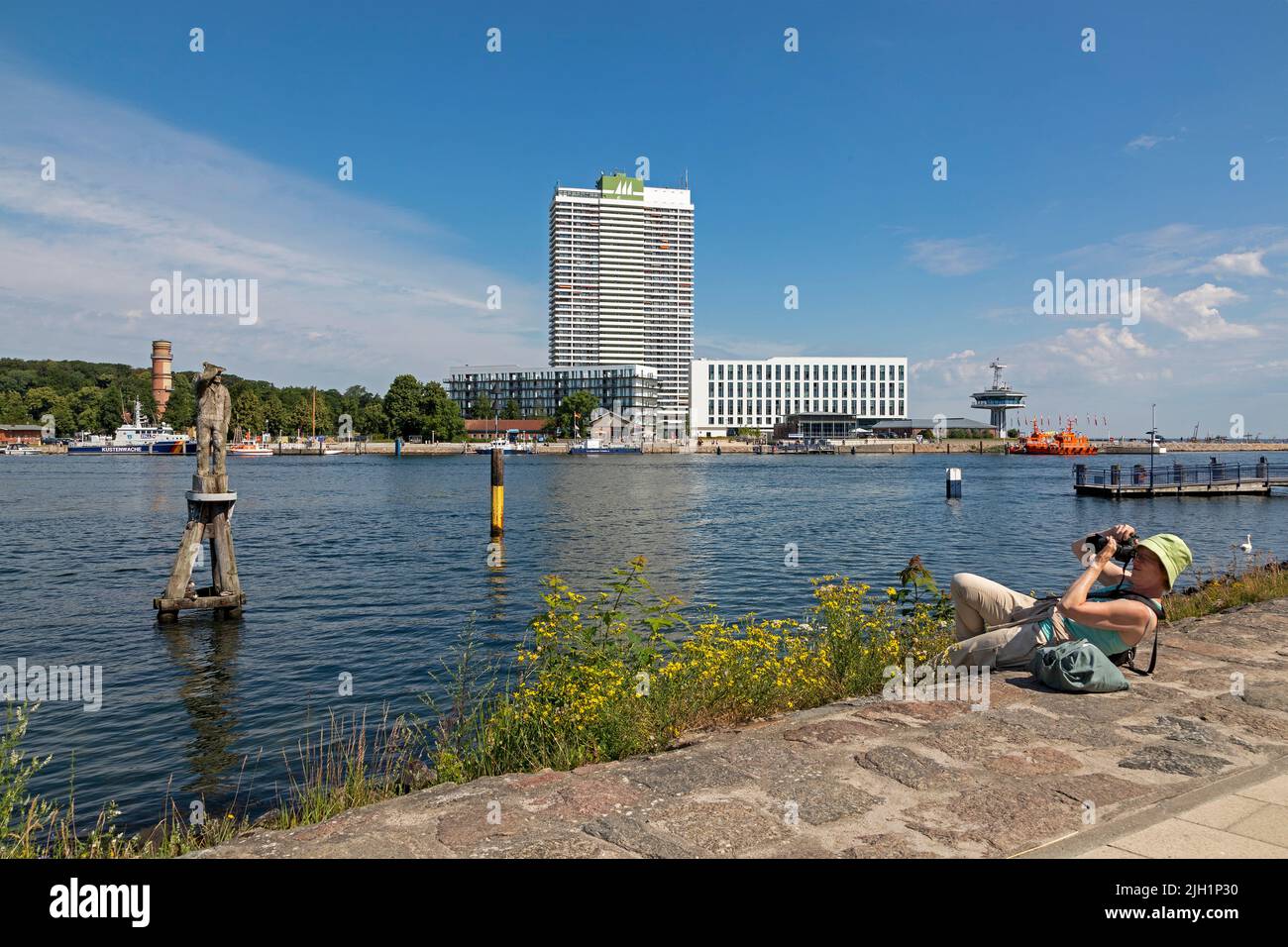 Donna sdraiata a terra per scattare foto, statua di Fiete, Faro Vecchio, Hotel Maritim, Travemünde, Lübeck, Schleswig-Holstein, Germania Foto Stock