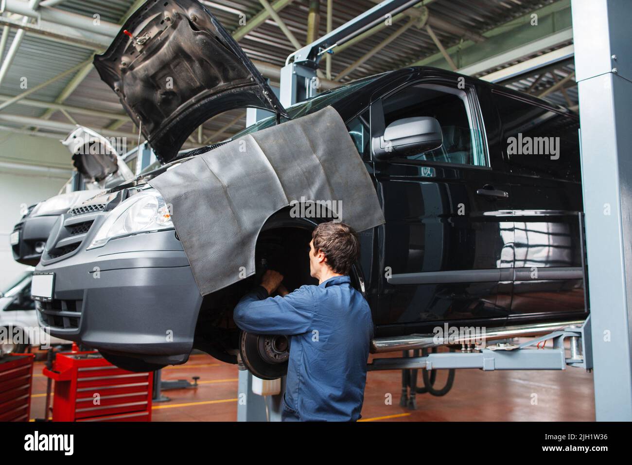 Addetto al controllo dell'impianto frenante in auto presso il garage Foto Stock