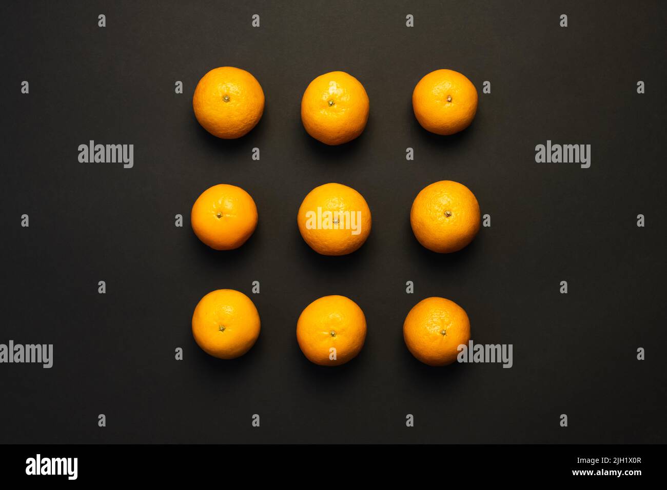Piatto con tangerini luminosi su sfondo nero Foto Stock