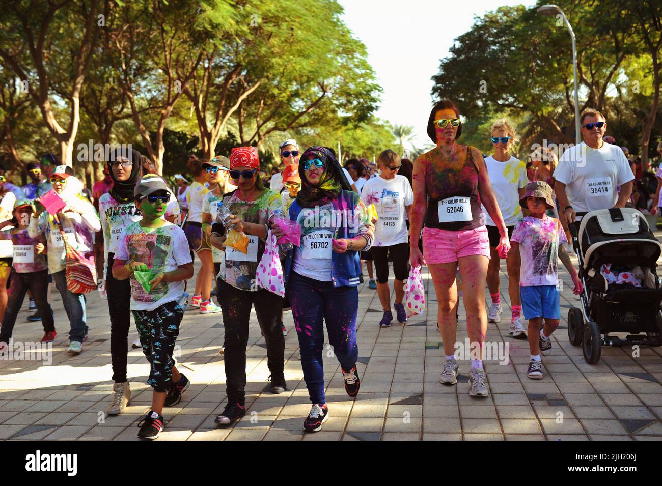 Diversi gruppi di persone (dall'età alla gara), tutti coperti di polvere colorata, camminano attraverso Zabeel Park a Dubai, Emirati Arabi Uniti per la Color Run. Foto Stock