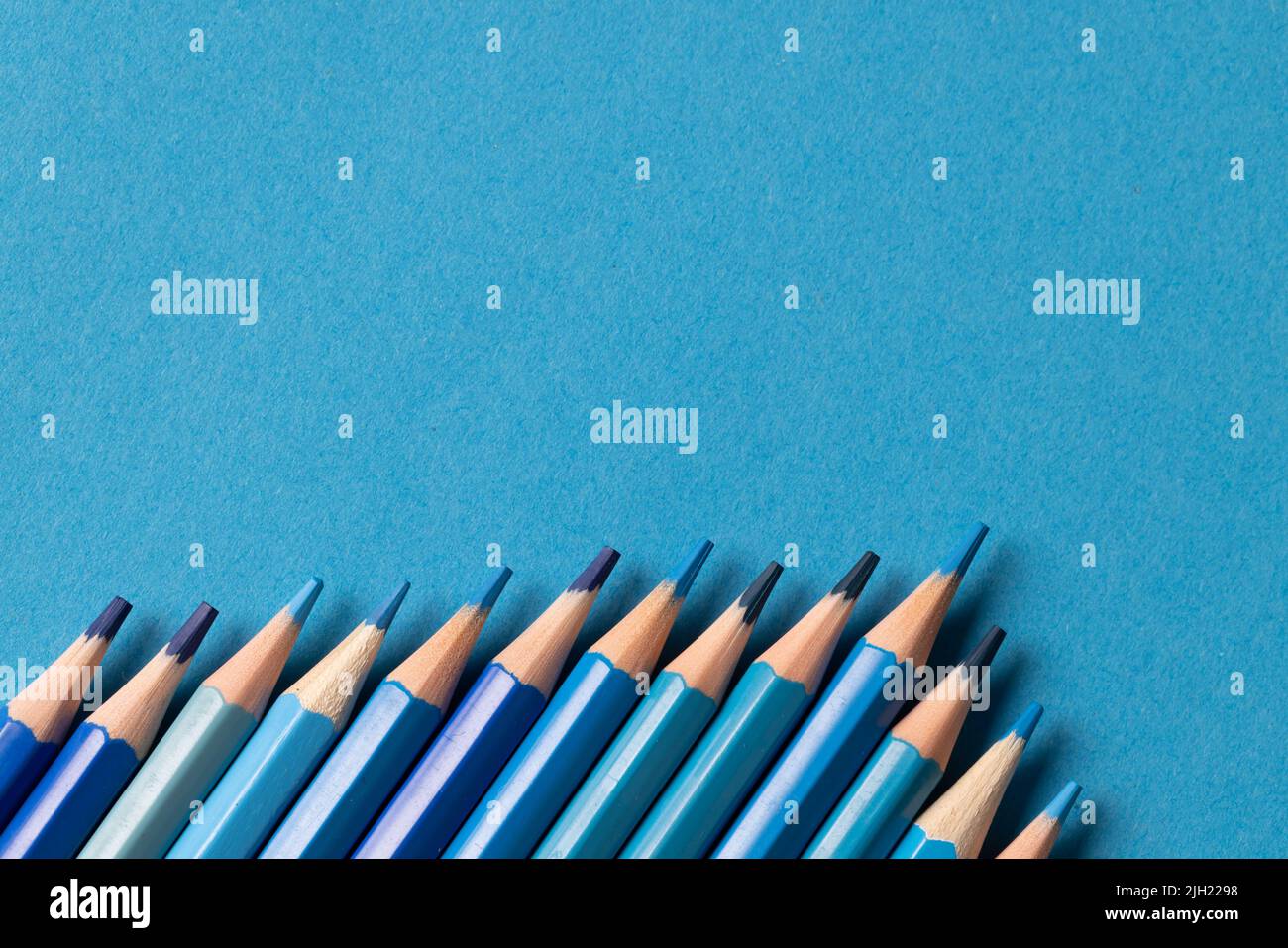 Immagine di una fila di diverse sfumature di pastelli blu su sfondo blu Foto Stock