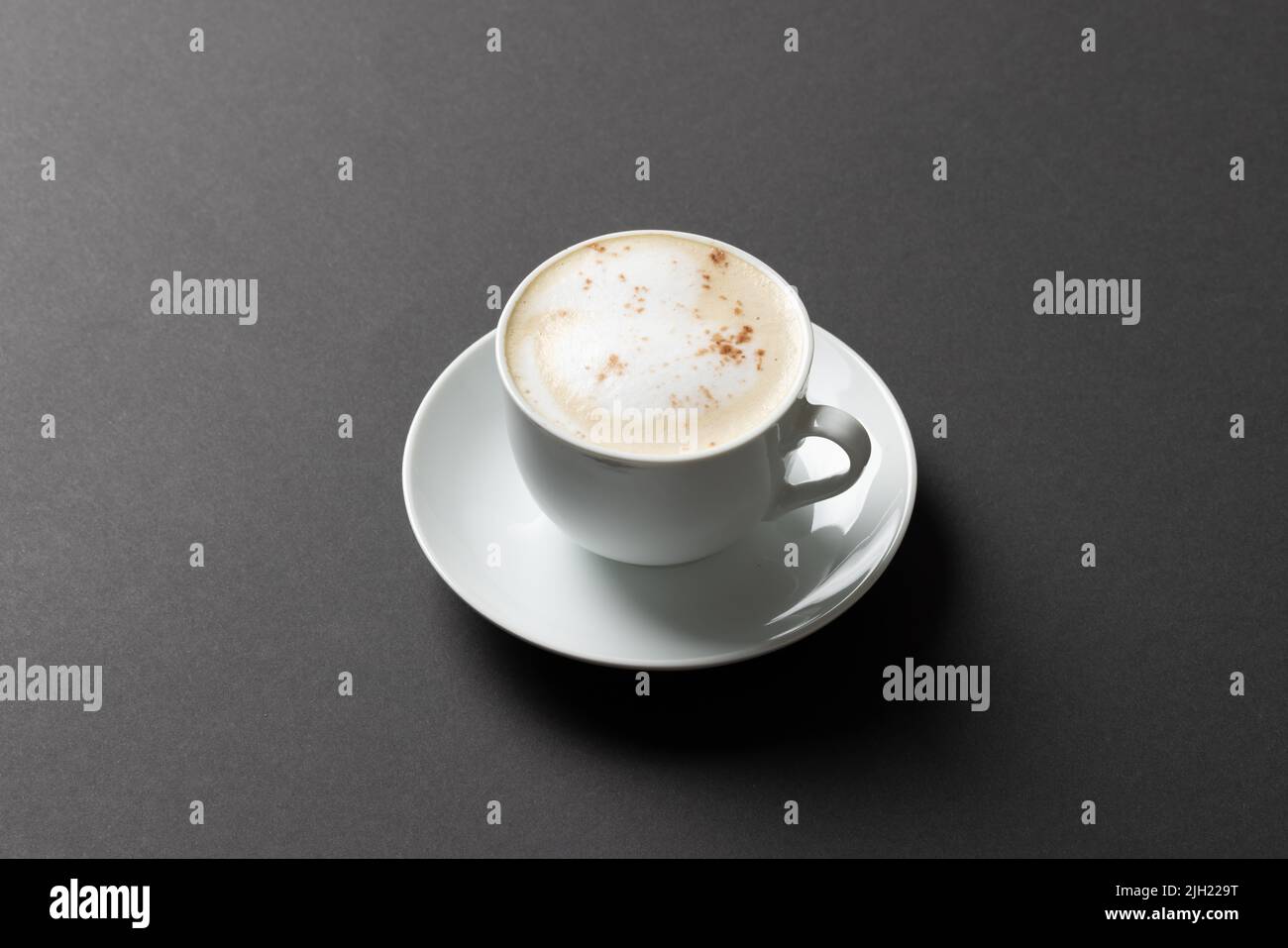 Immagine di una tazza di caffè bianca con latte su sfondo nero Foto Stock
