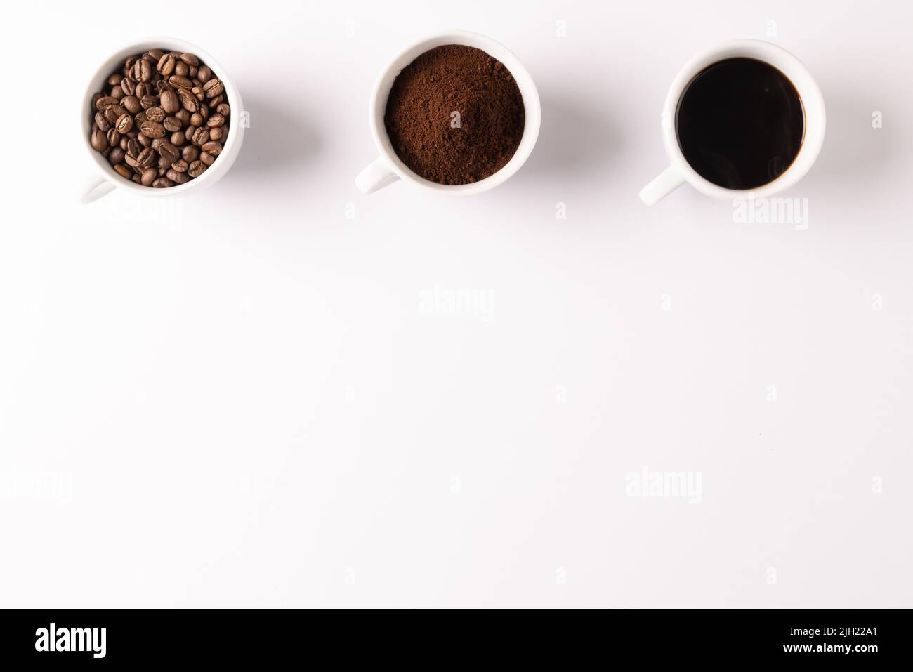 Immagine di tre tazze piene di caffè macinato, chicchi di caffè e caffè su sfondo bianco Foto Stock