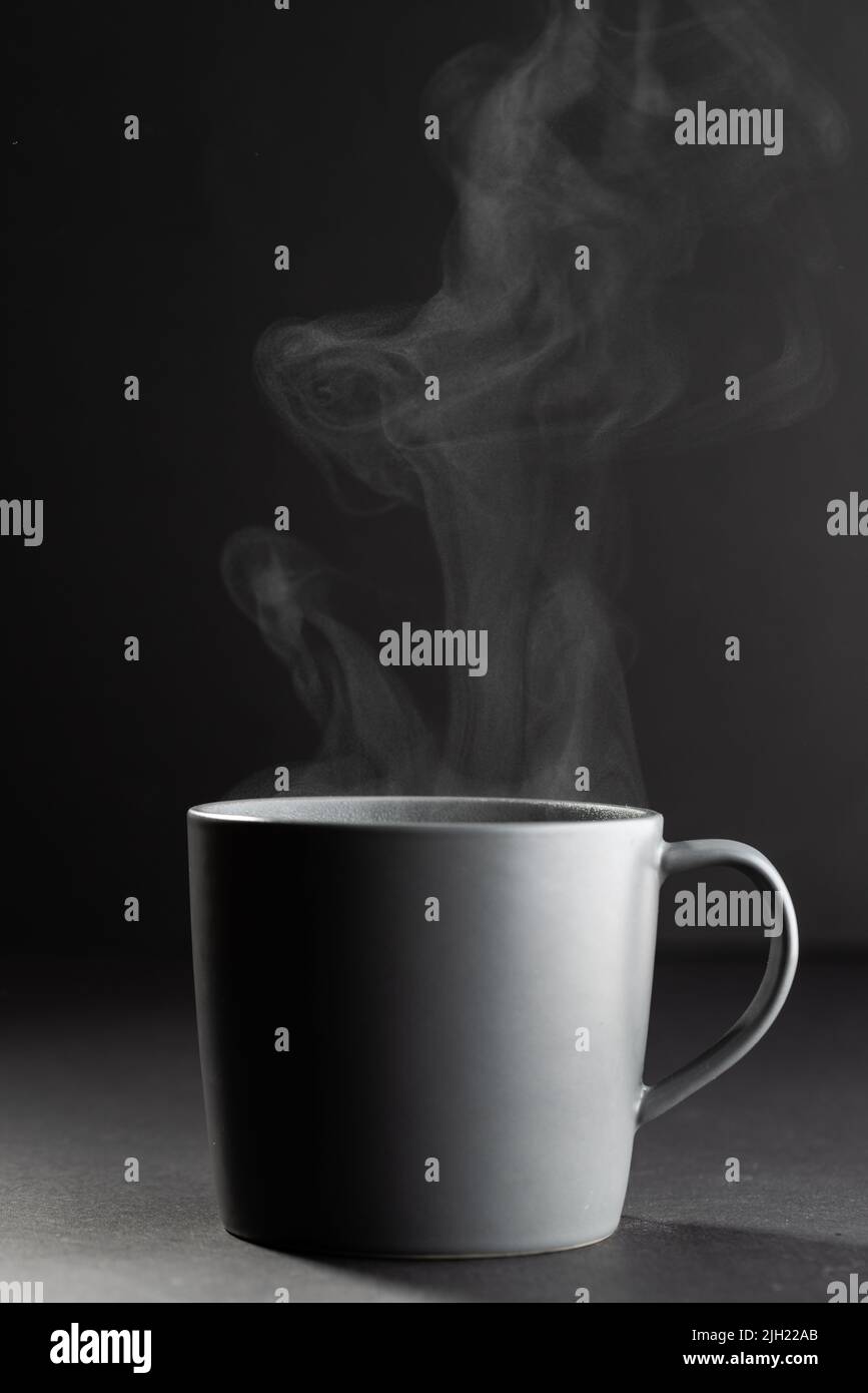 Immagine di una tazza grigia di caffè nero caldo su sfondo nero Foto Stock