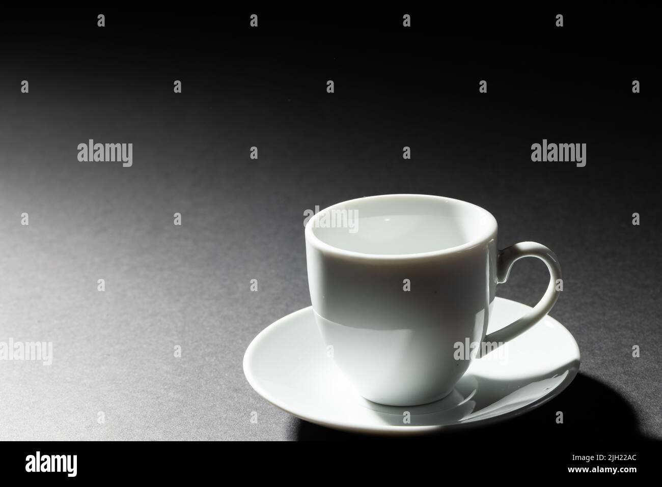 Immagine della tazza di caffè bianca vuota e della piastra su sfondo nero Foto Stock