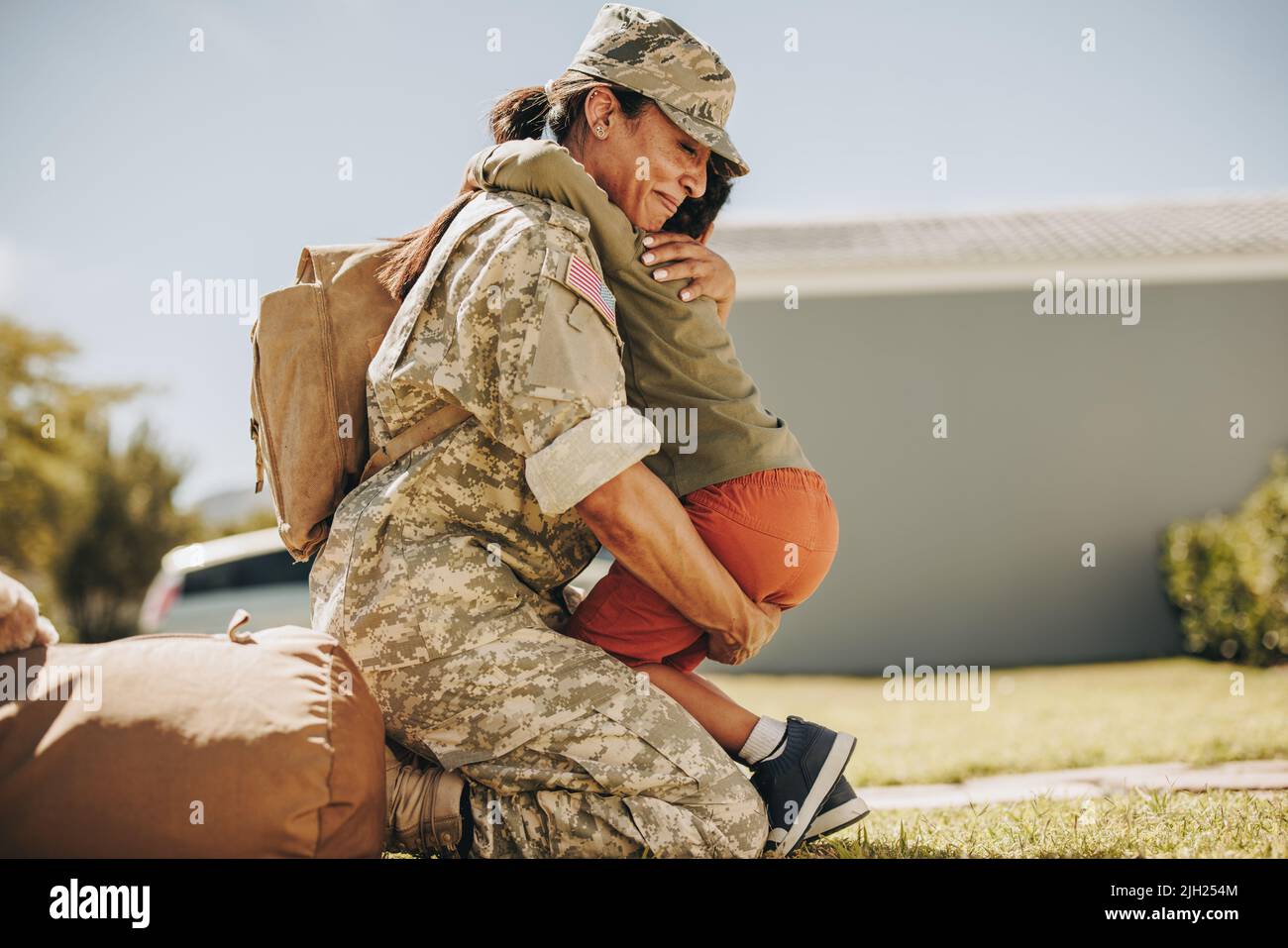 Mamma militare che abbraccia suo figlio dopo essere tornato a casa dall'esercito. Coraggiosa soldato femminile che ha una riunione emotiva con il suo bambino dopo mi Foto Stock