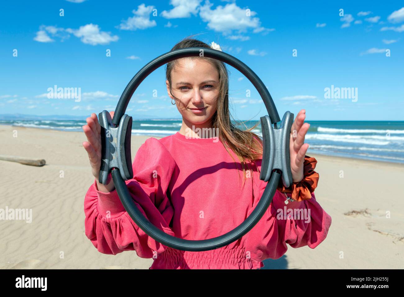 giovane donna che mostra pilates hoop sulla spiaggia Foto Stock