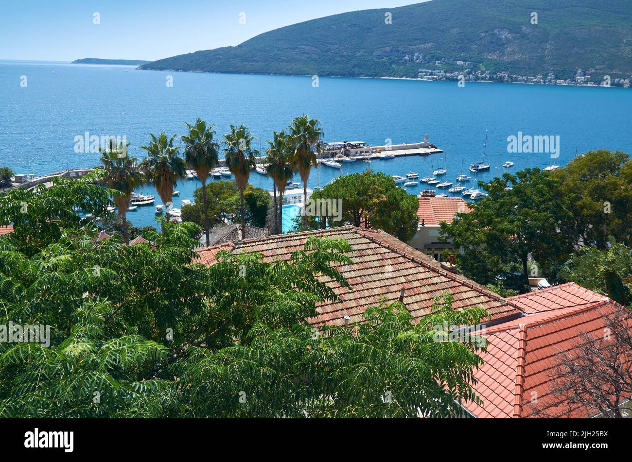 Vista aerea su una baia con tetti rossi, palme e un mare con barche e yacht Foto Stock