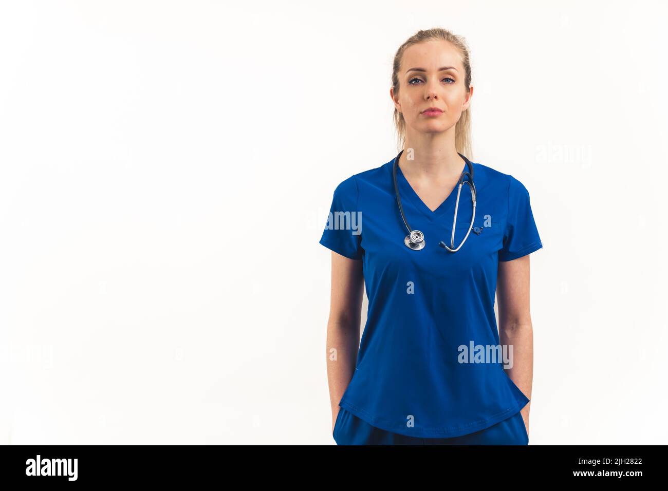 Donna caucasica forte, indipendente, potente e professionale come operatore sanitario - infermiere, medico, specialista, in piedi in una uniforme blu scuro e guardando la macchina fotografica con fiducia. Immagine media dello spazio di copia isolato su sfondo bianco. Foto di alta qualità Foto Stock