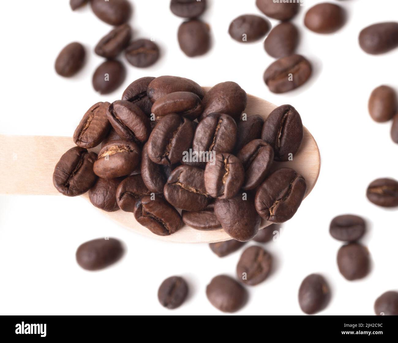 Chicchi di caffè appena tostati in un cucchiaio di legno isolato su sfondo bianco, vista dall'alto Foto Stock