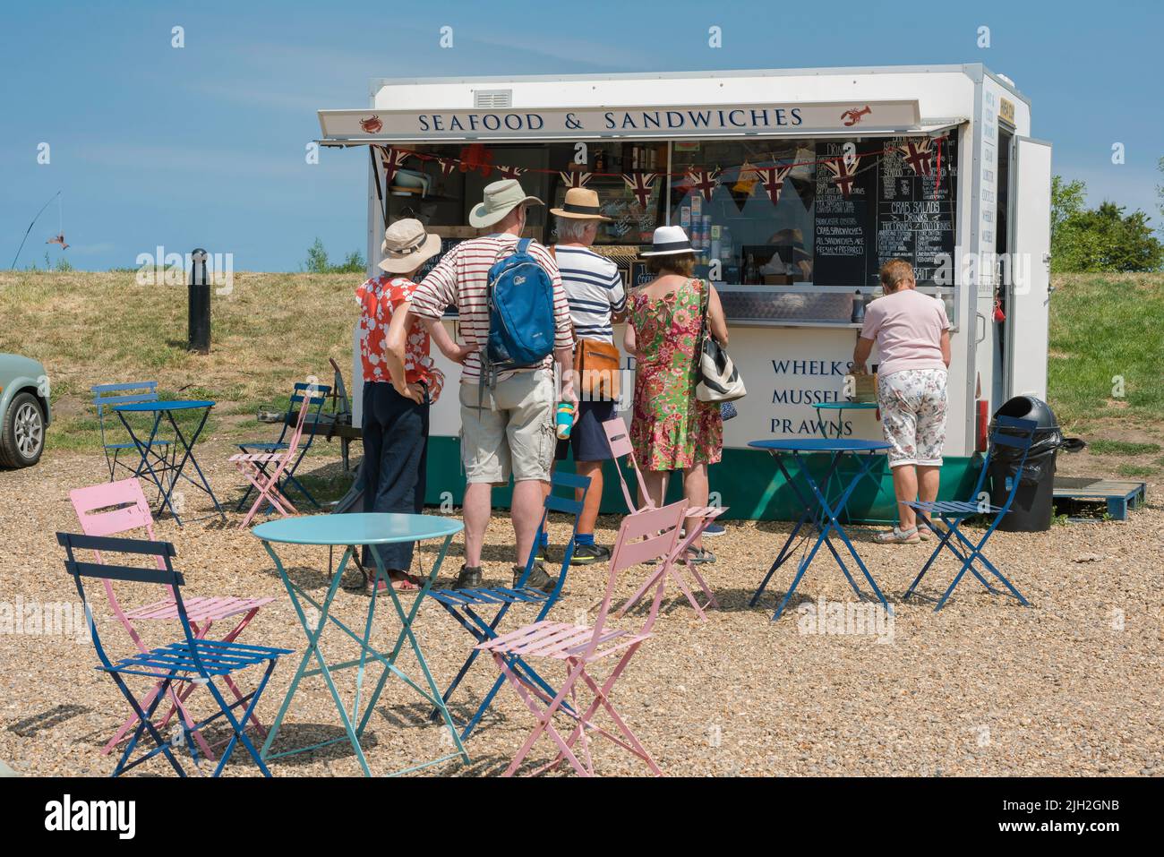 La costa nord del Norfolk, guarda in estate le persone che si accanono in una bancarella di pesce e sandwich nel villaggio di mare nord del Norfolk di Blakeney, Inghilterra, Regno Unito Foto Stock