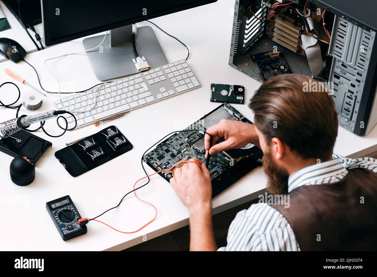 Ingegnere che esegue il test del circuito del computer con multitester Foto Stock