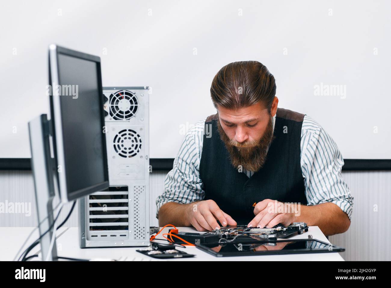 Ingegnere bearded che monta il computer sul posto di lavoro Foto Stock