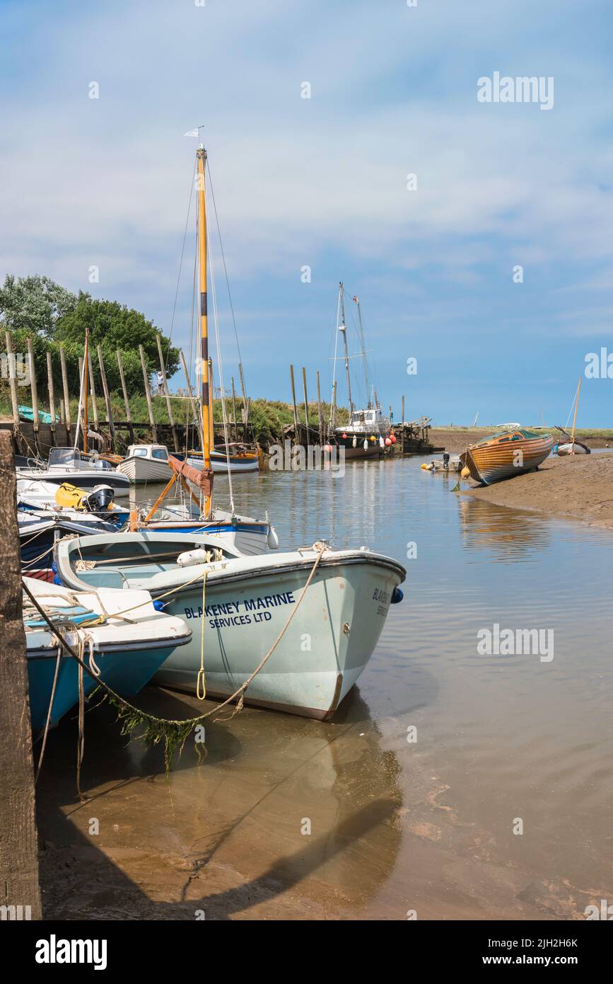 Blakeney Quay, vista in estate delle barche ormeggiate lungo il molo nel villaggio nord di Norfolk di Blakeney, Norfolk, Inghilterra, Regno Unito Foto Stock