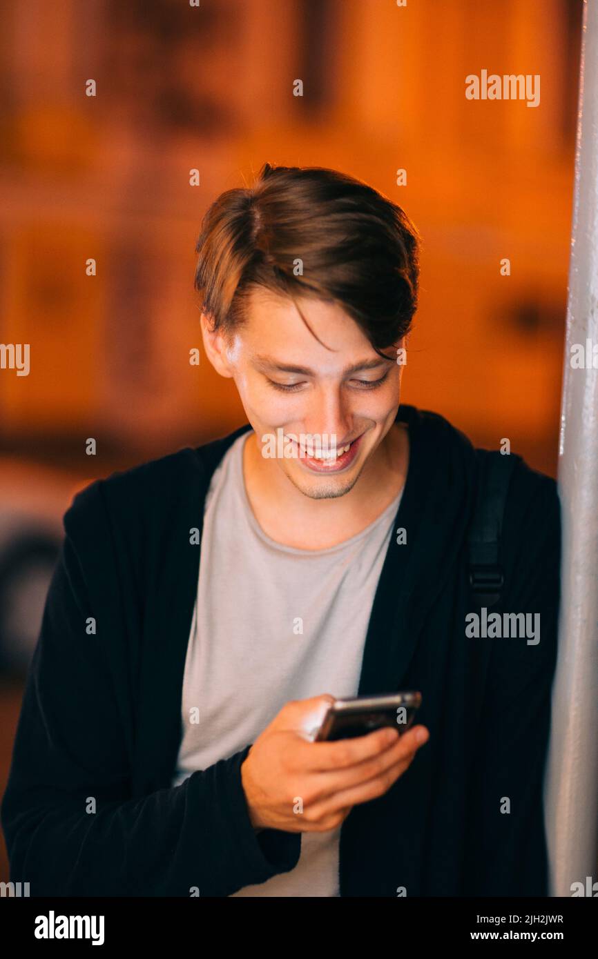 Ragazzo sorridente con smartphone nella città notturna Foto Stock