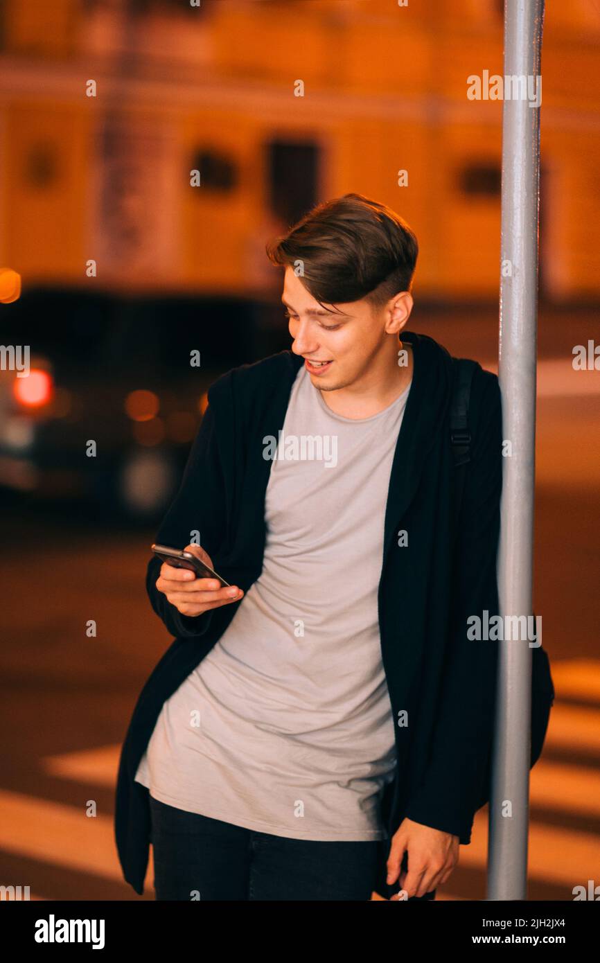 Ragazzo sorridente con smartphone nella città notturna Foto Stock