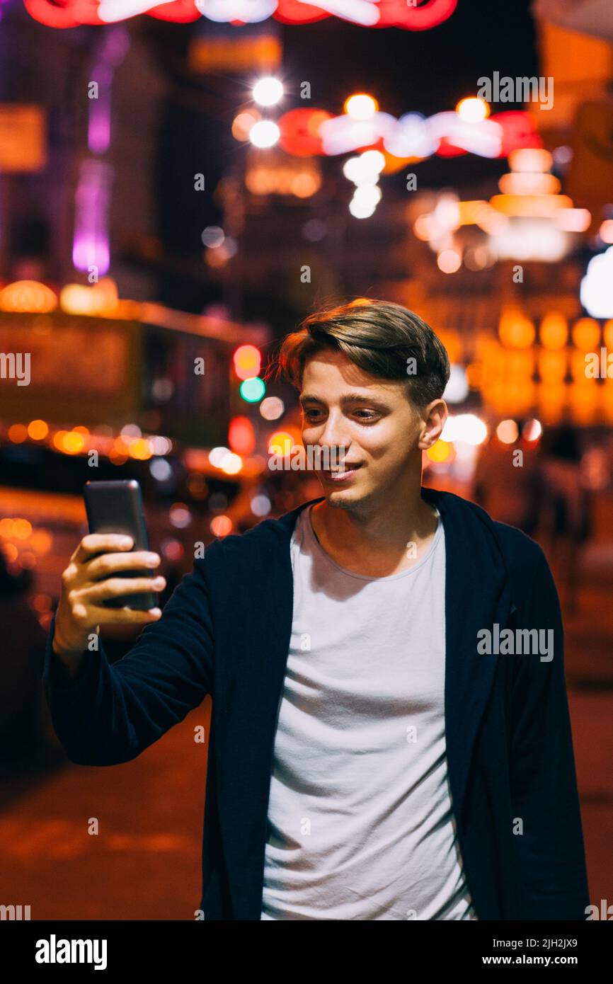 Il giovane scatta foto sullo smartphone in città Foto Stock