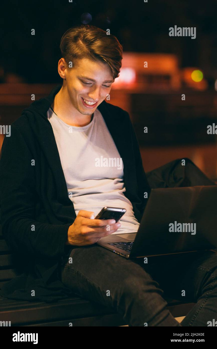 Ragazzo sorridente che legge il messaggio sullo smartphone Foto Stock