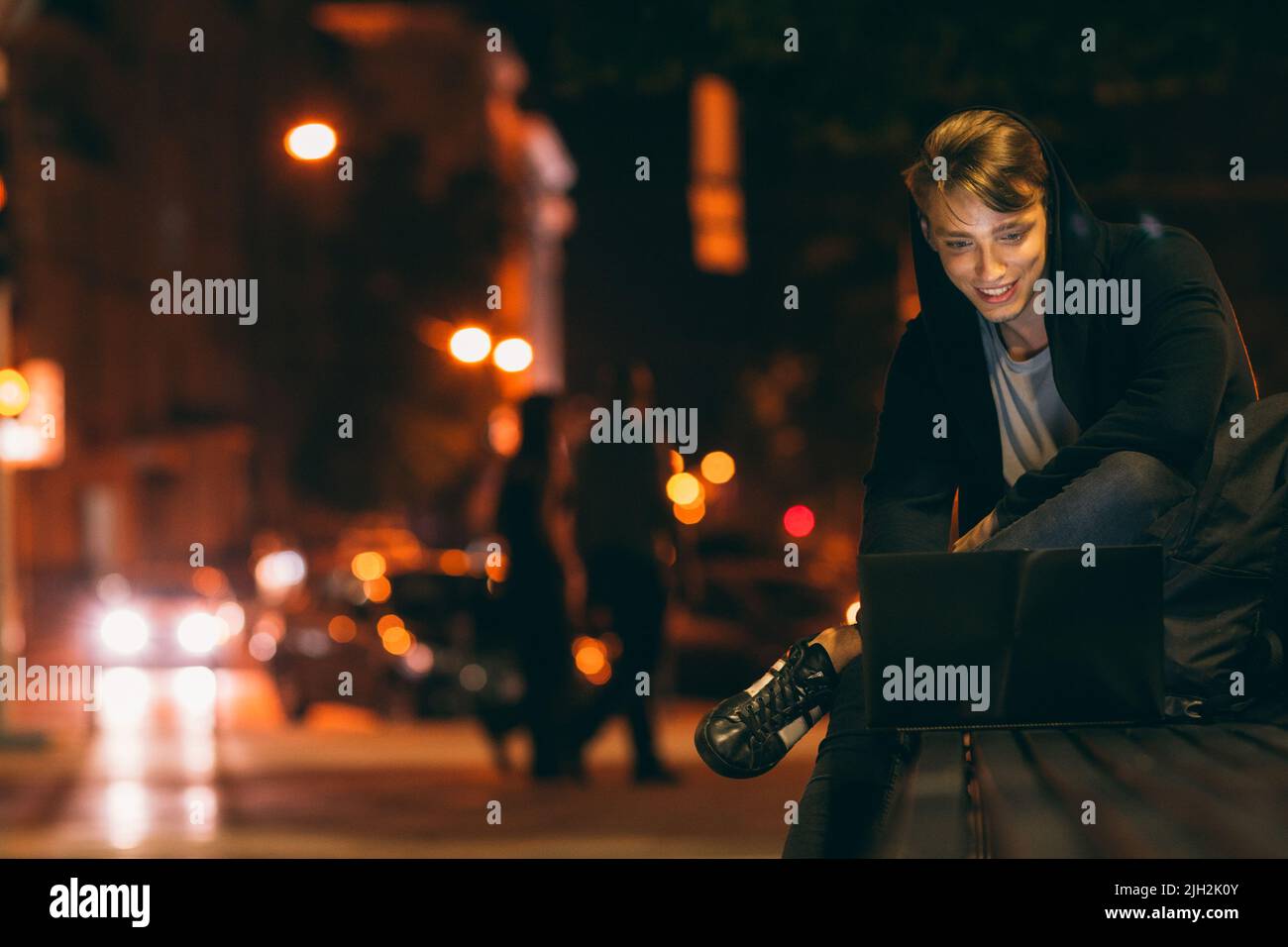Giovane uomo con computer portatile nella città di notte Foto Stock