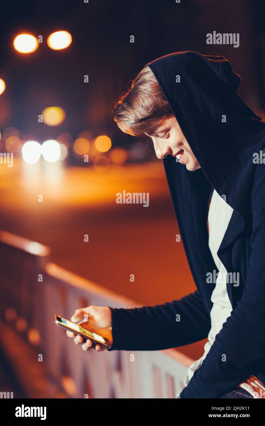 Bel giovane uomo che usa lo smartphone in città Foto Stock