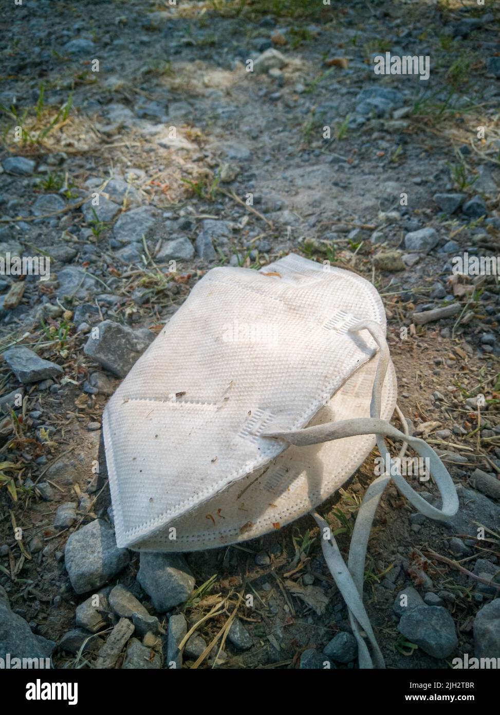 Vecchia, sporca e scartata FFP2-maschera si trova su strada agricola. Simbolo di immondizia e inquinamento. Foto Stock