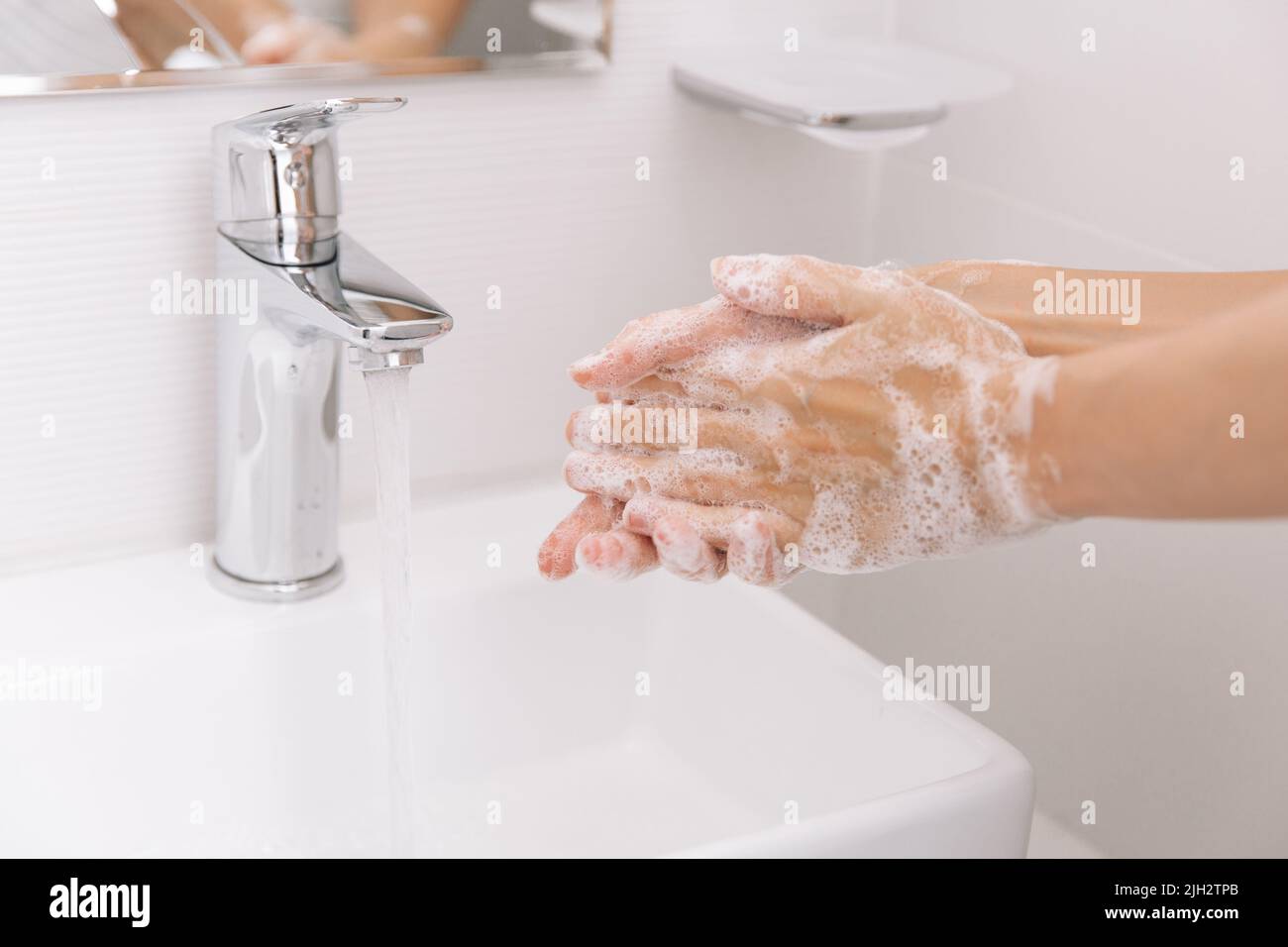 Lavarsi le mani sotto il rubinetto dell'acqua corrente. Dettagli della mano del concetto di igiene. Lavando le mani strofinando con sapone per la prevenzione del virus corona, igiene per fermare Foto Stock