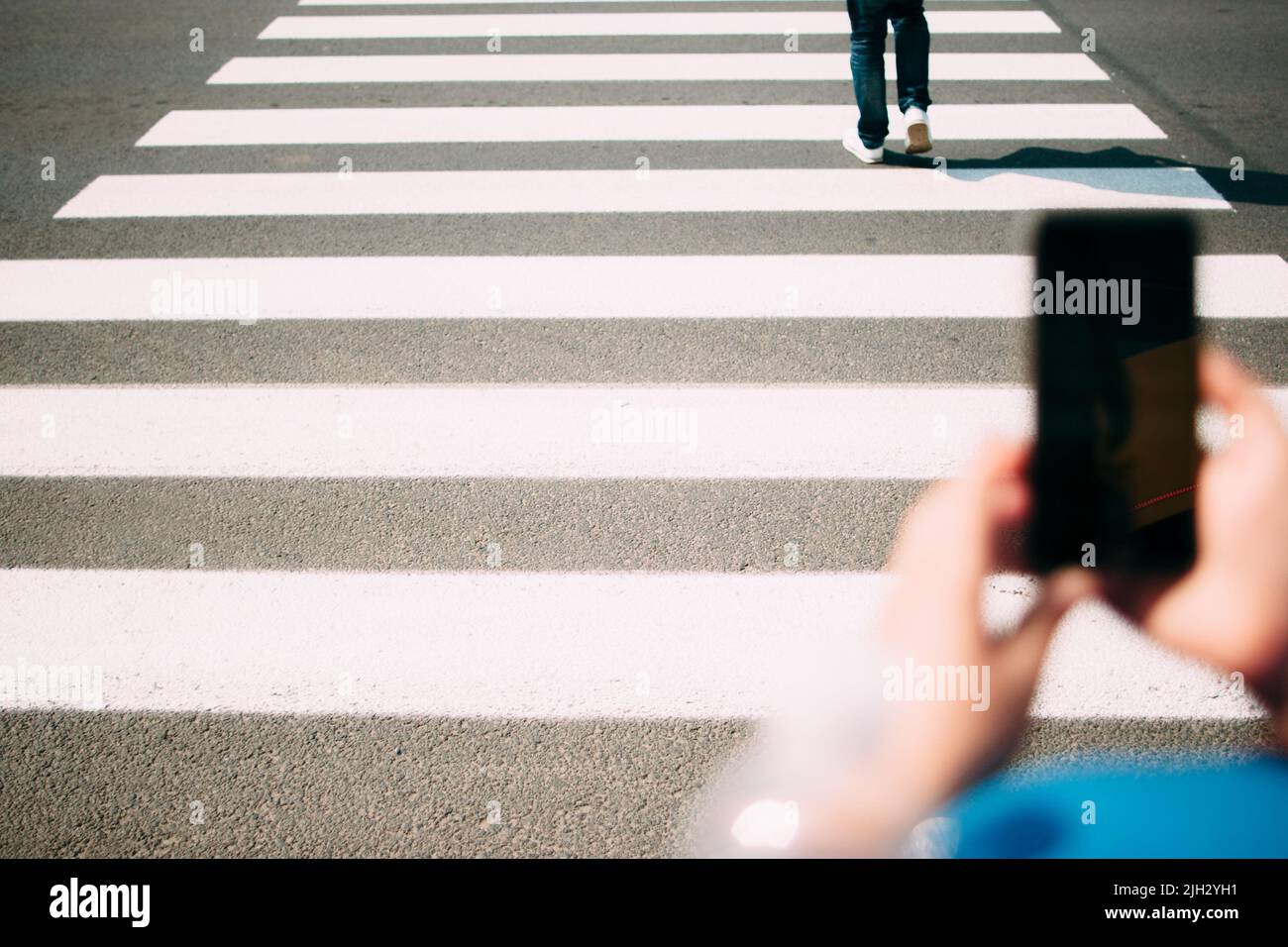 Primo piano zebra pedonale, smartphone in primo piano Foto Stock