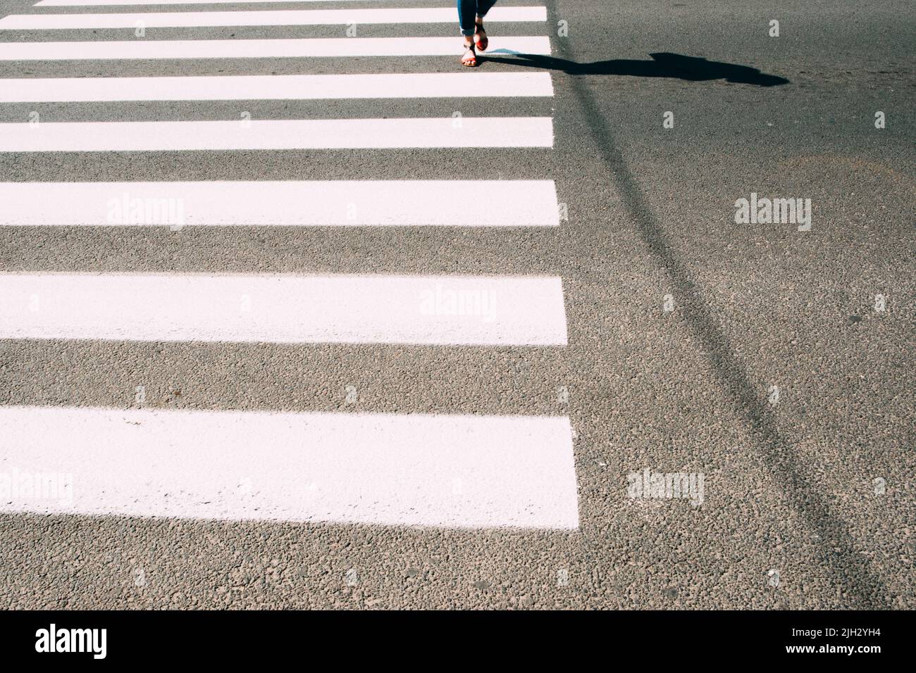 Zebra pedonale con gambe a piedi e asfalto Foto Stock