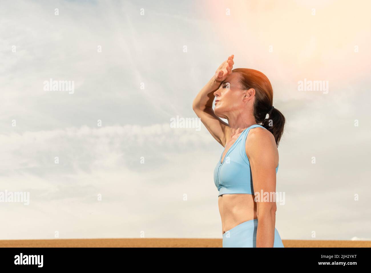 Donna sportiva all'aperto al sole, sofferente con il calore Foto Stock