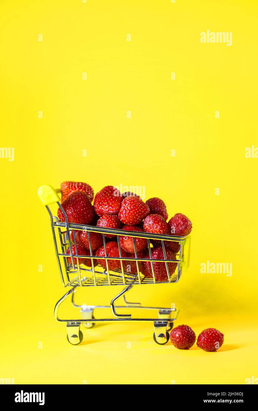 un supermercato pieno di fragole rosse su sfondo giallo. Foto Stock