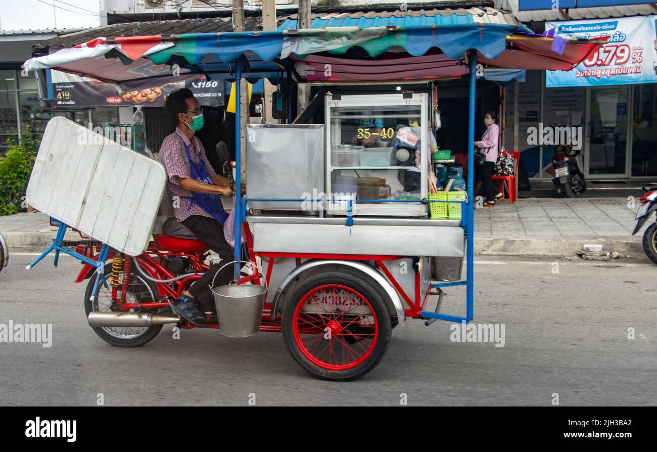 SAMUT PRAKAN, THAILANDIA, MAGGIO 12 2022, Un giro venditore su un triciclo motorizzato su una strada. Foto Stock