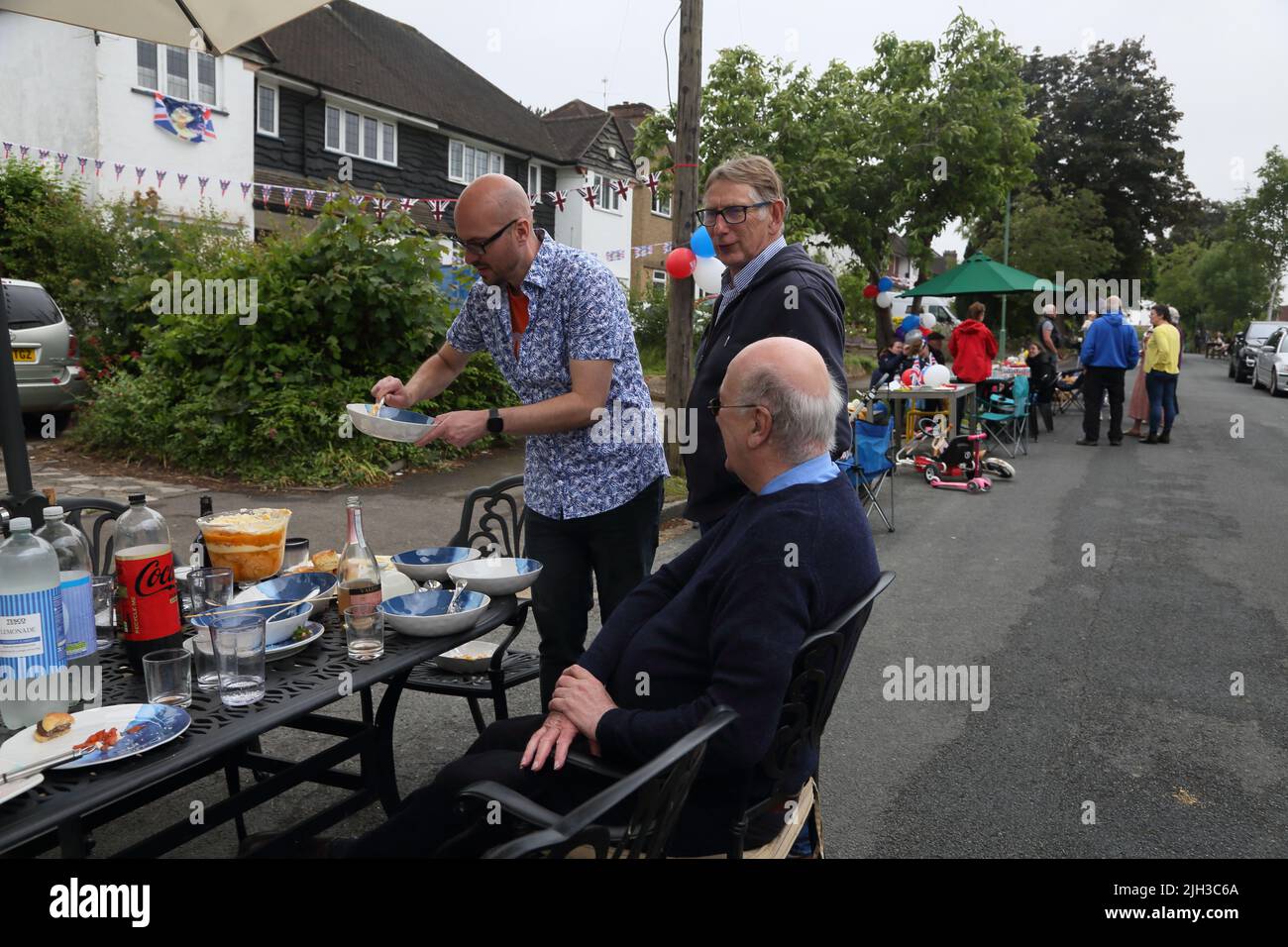 Uomo che serve il Limone 'Platinum Pudding' e il Trifle Amaretti al Street Party che celebra il Giubileo del platino della Regina Elisabetta II, Surrey Inghilterra Foto Stock