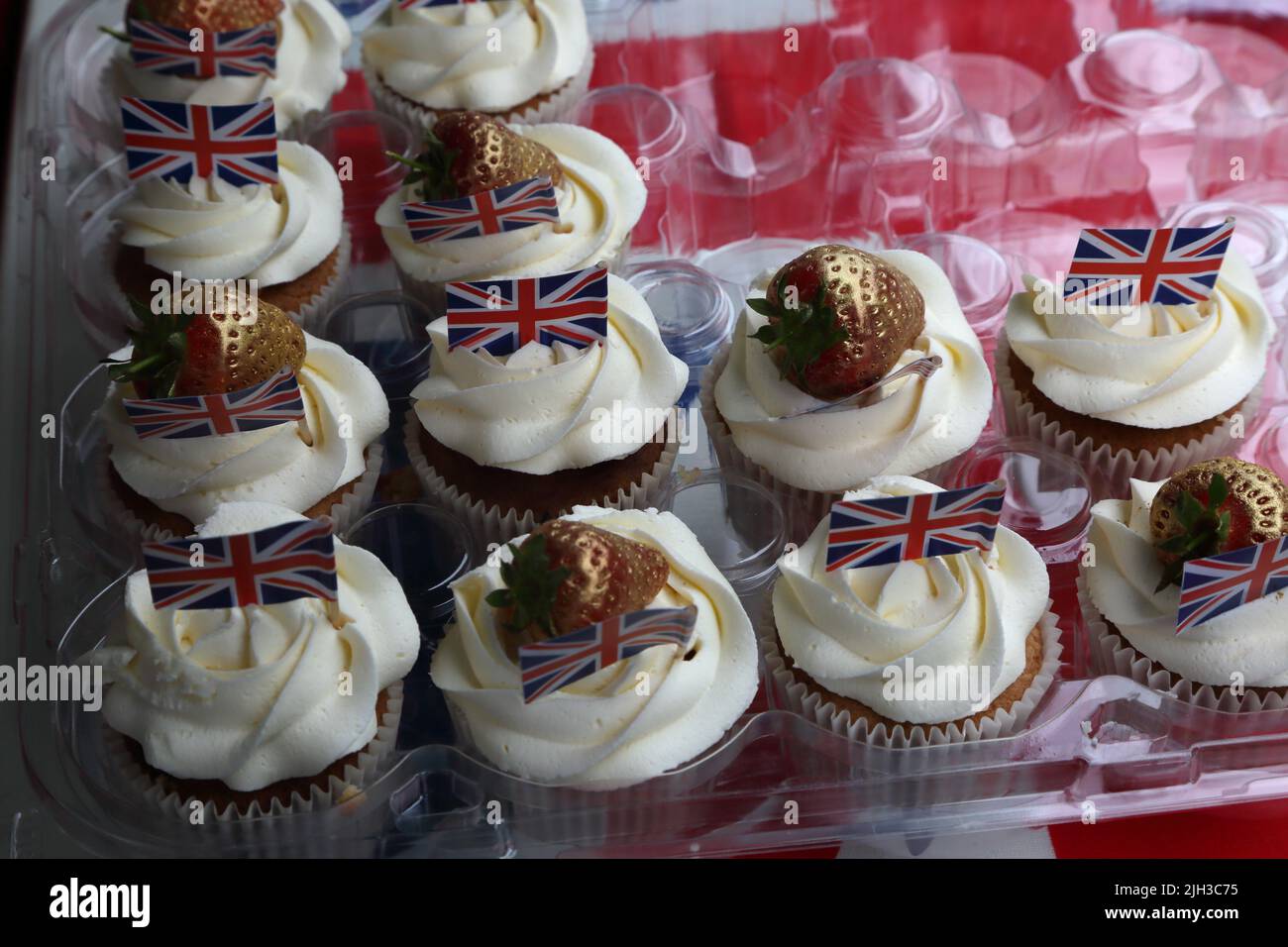 Cupcake fatti in casa con fragole d'oro e Union Jack Flags al Street Party che celebra la Regina Elisabetta II Platinum Jubilee Surrey Inghilterra Foto Stock