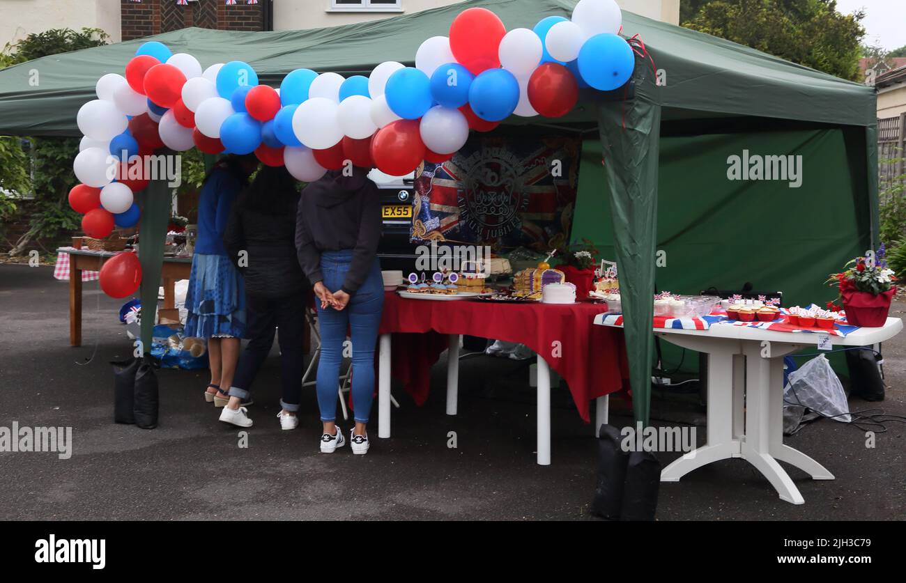 Donne che guardano spugne fatte in casa e Cupcakes su torta Stall a Street Party celebrare Queen Elizabeth II Platinum Jubilee Surrey Inghilterra Foto Stock