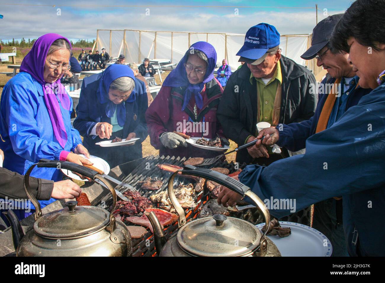 Gli anziani indigeni di Dene stanno intorno alla griglia alla festa della comunità in estate, nella comunità settentrionale di Deline, territori del nord-ovest, Canada Foto Stock