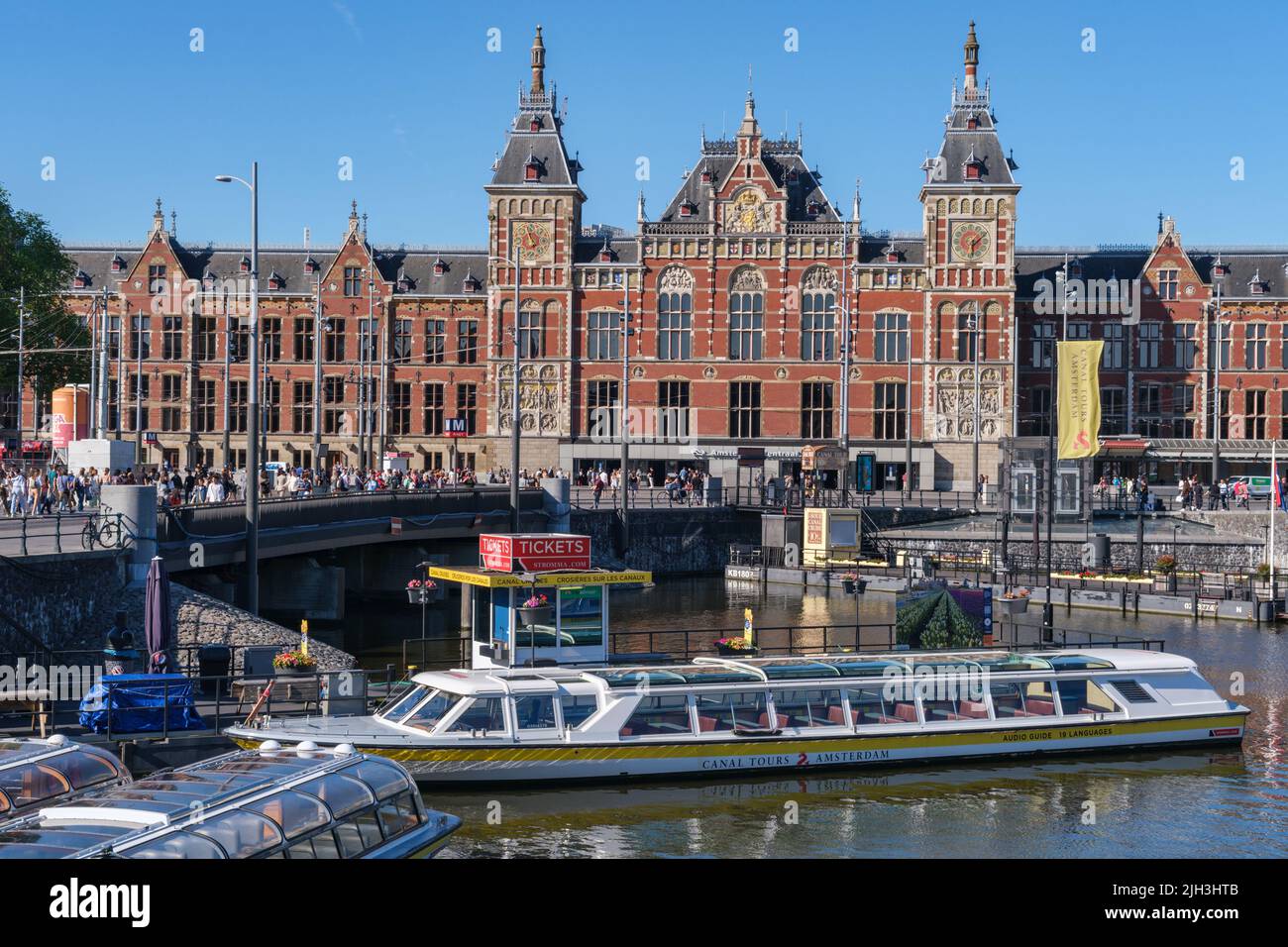 Amsterdam, Paesi Bassi - 22 giugno 2022: Crociera turistica in barca sul canale Damrak, con la stazione centrale di Amsterdam sullo sfondo Foto Stock