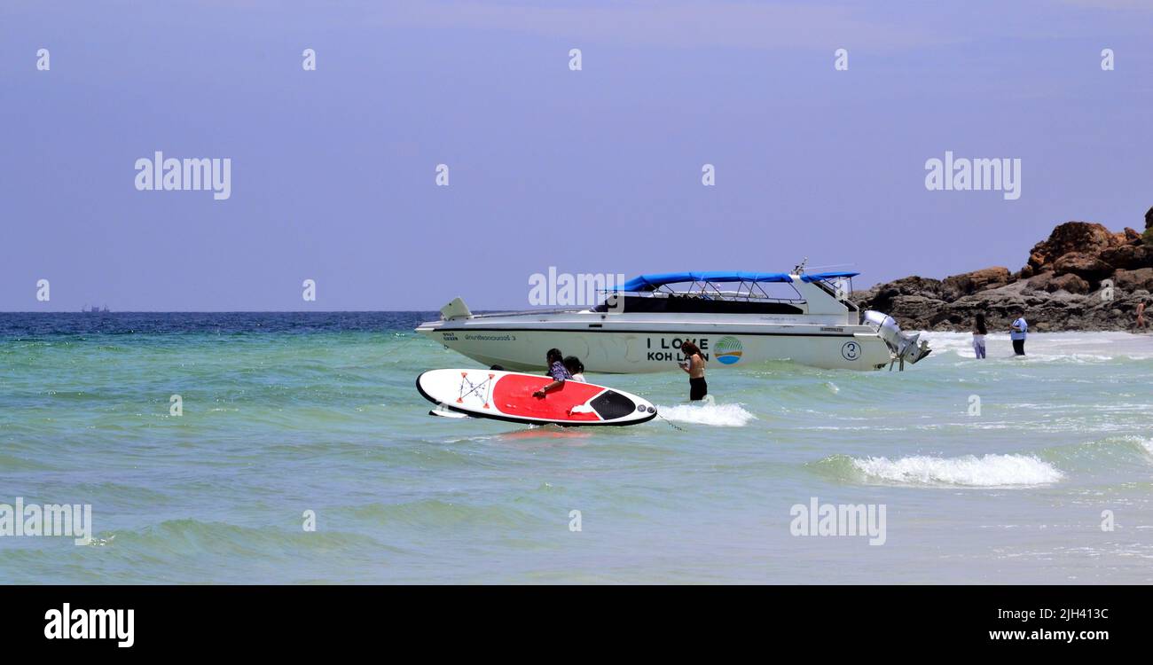 Un uomo porta una pedalata vicino a un motoscafo in mare a Tien Beach sull'isola di Koh Larn, che può essere spelt Ko Larn o Ko Laan o Ko LAN, Thailandia, Asia. Foto Stock