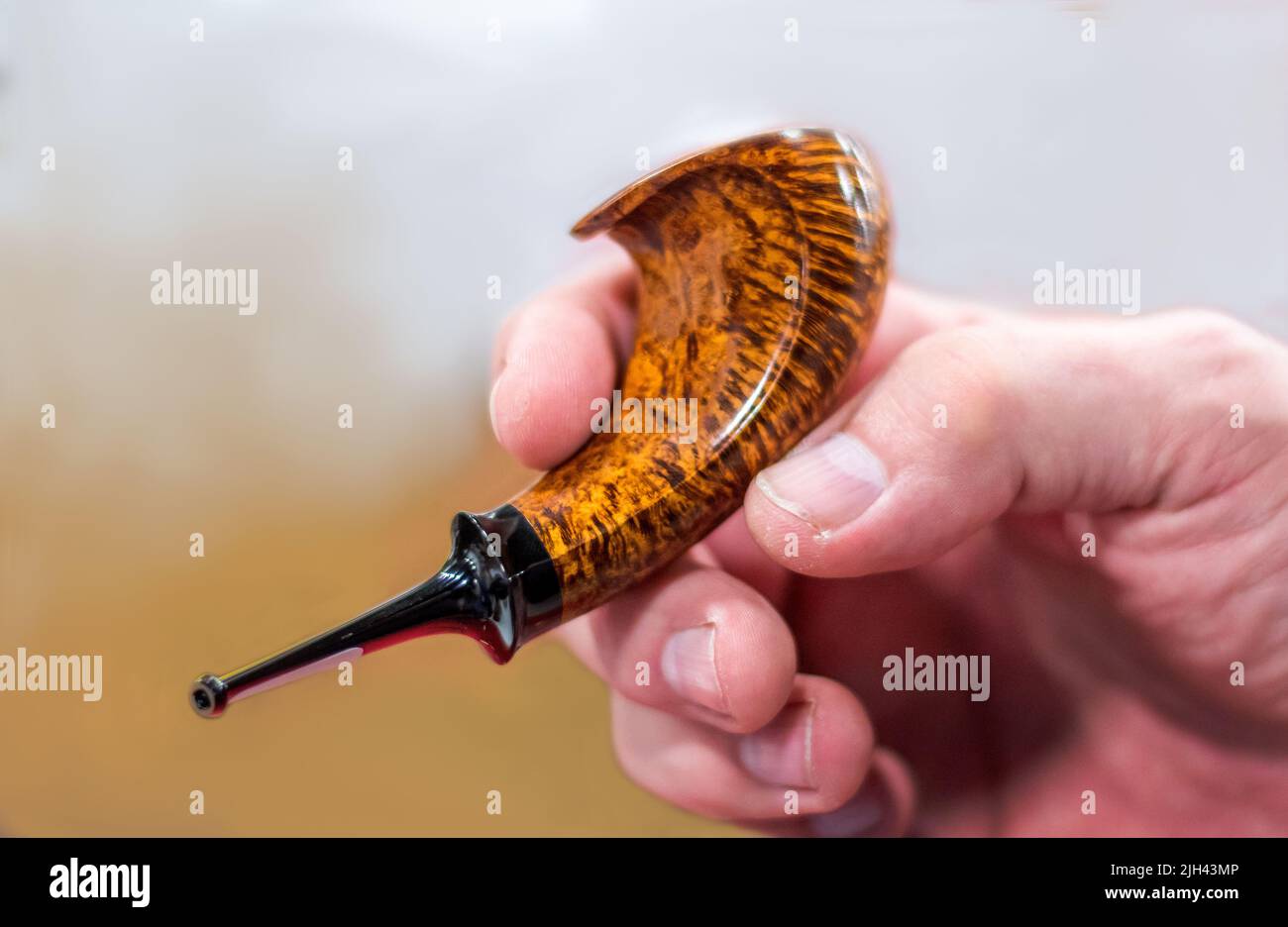 La mano dell'uomo tiene un tubo del corno del briar, lucidato splendidamente e tiene il suo tabacco fumante favorito Foto Stock